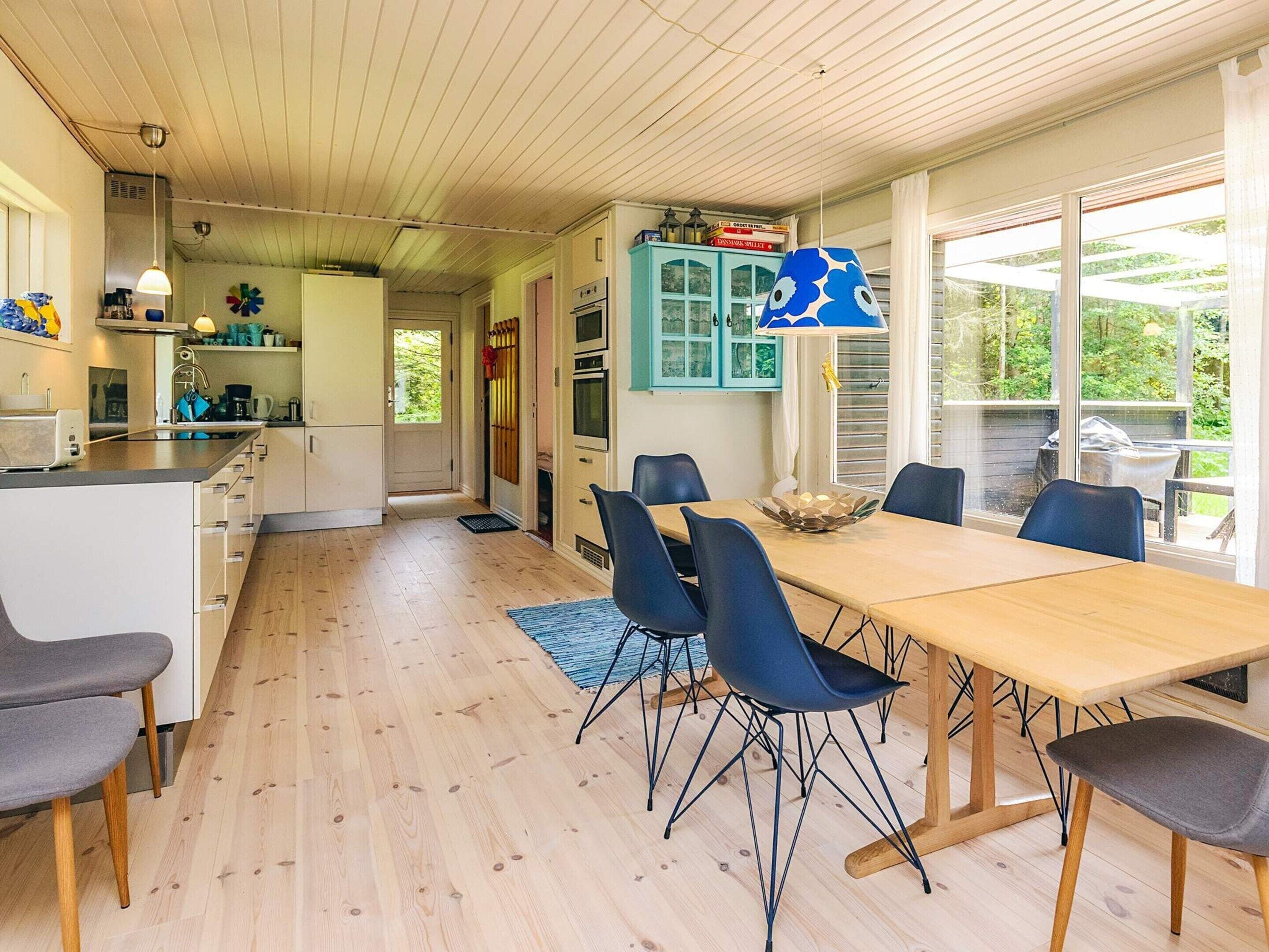 Una cocina moderna con armarios blancos, una mesa de comedor de madera y sillas azules.
