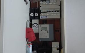 A room with electrical panels, a fire extinguisher, and a water heater.