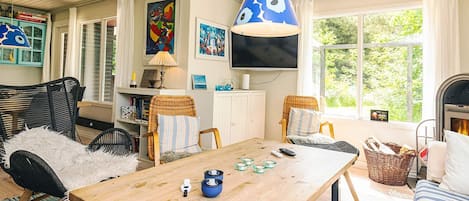 Ein gemütliches Wohnzimmer mit einem Holztisch, Korbstühlen und einer blauen Hängelampe.