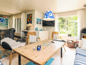 A cozy living room with a wooden table, wicker chairs, and a blue hanging lamp.