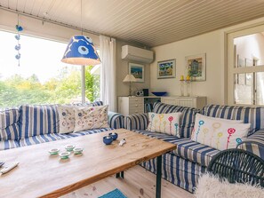 A cozy living room with striped sofas, a wooden coffee table, and a hanging blue lamp.