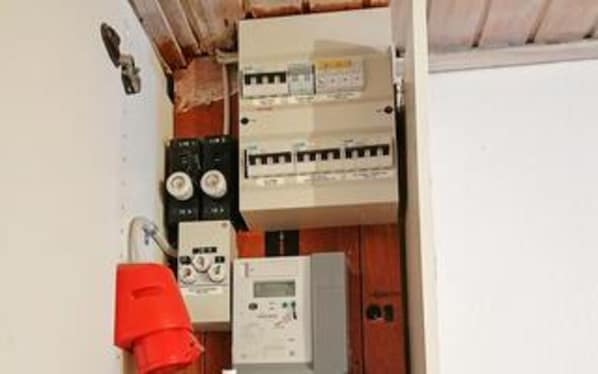An electrical panel with circuit breakers and a control panel, indicating a utility area in a building.