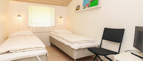 Un dormitorio con dos camas individuales, un escritorio con silla, un televisor y una ventana con cortinas.