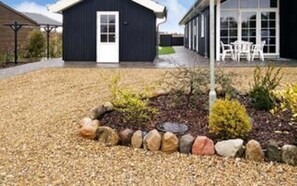 A building with a dark exterior, a white door, and a gravel driveway. - 10 Person Holiday Home in Ansager-by Traum (Ansager)