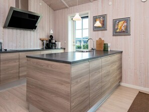 A modern kitchen with a central island, wooden cabinetry, a built-in microwave, and a window providing natural light. - 10 Person Holiday Home in Ansager-by Traum (Ansager)