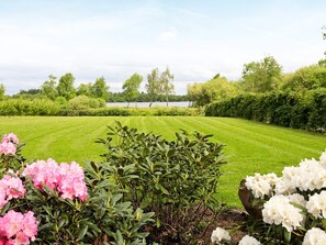 A well-maintained lawn with a variety of flowering shrubs in the foreground.
