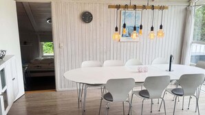 Et moderne spiseområde med et rundt bord, seks stole, et ur og en pendellampe.