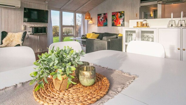 En moderne stue med spisebord, sofaer og fjernsyn.
