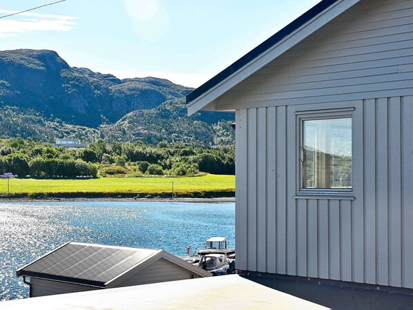 A building with a large window overlooking a body of water and a mountainous landscape. - 8 Person Holiday Home in Oksvoll (Orland)
