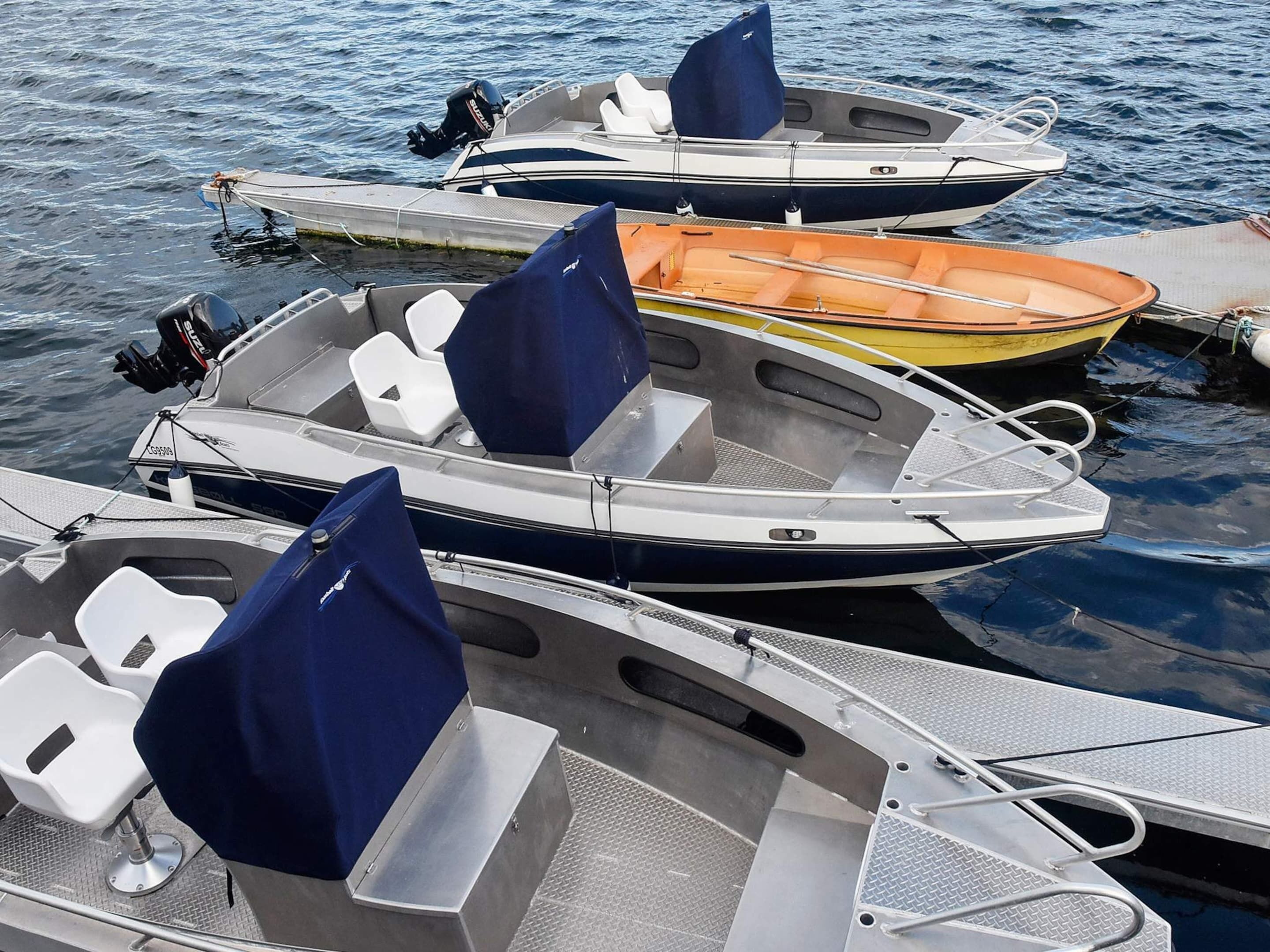 A row of boats docked at a marina with seating and a covered area.