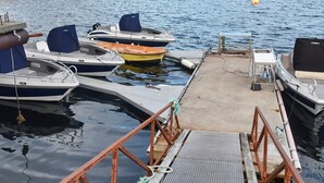 A dock with several boats moored, a concrete platform, and a mountainous landscape in the background. - 8 Person Holiday Home in Oksvoll (Orland)