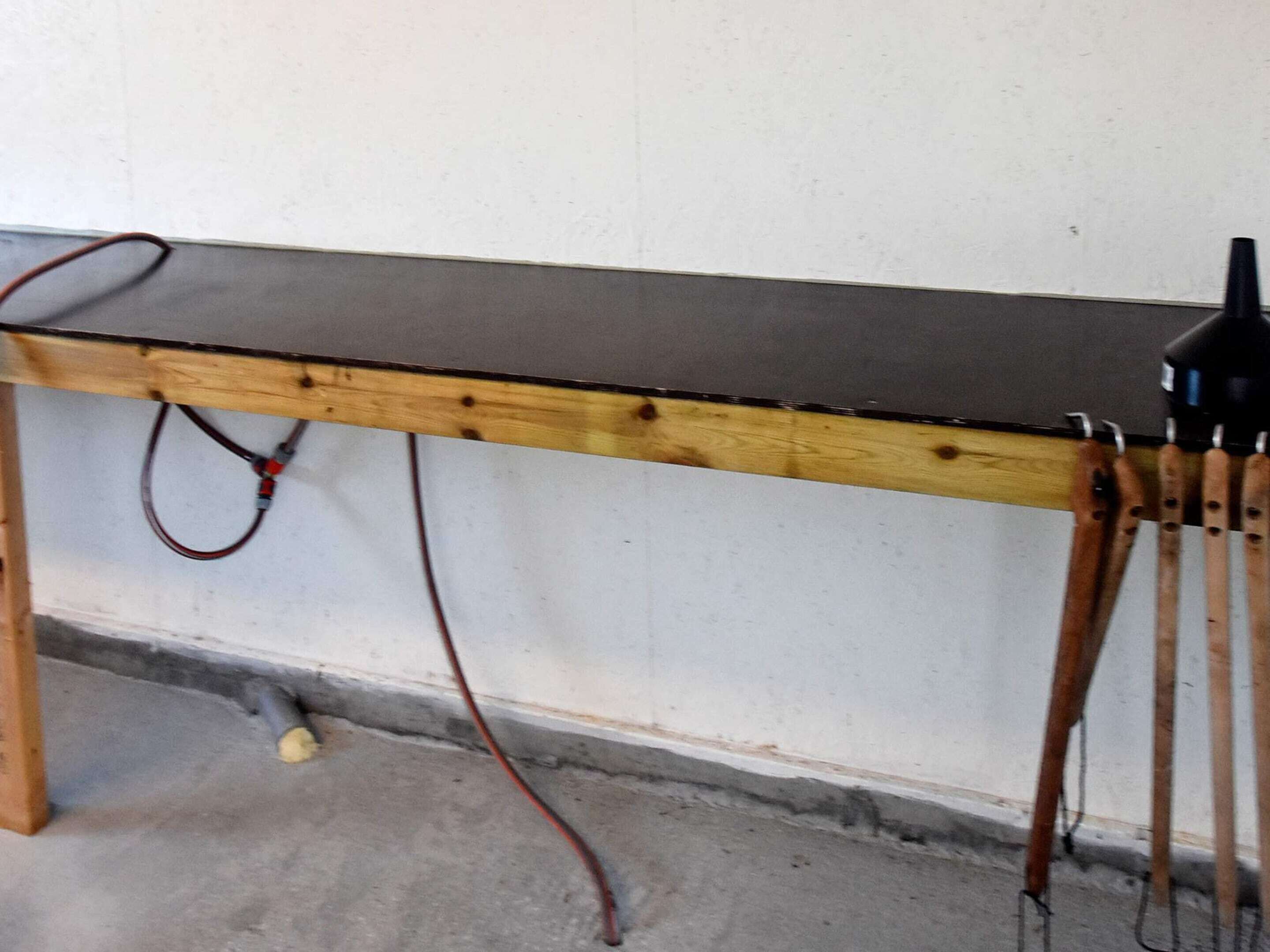 A wooden table with a black top, a red cable, and a black lamp.