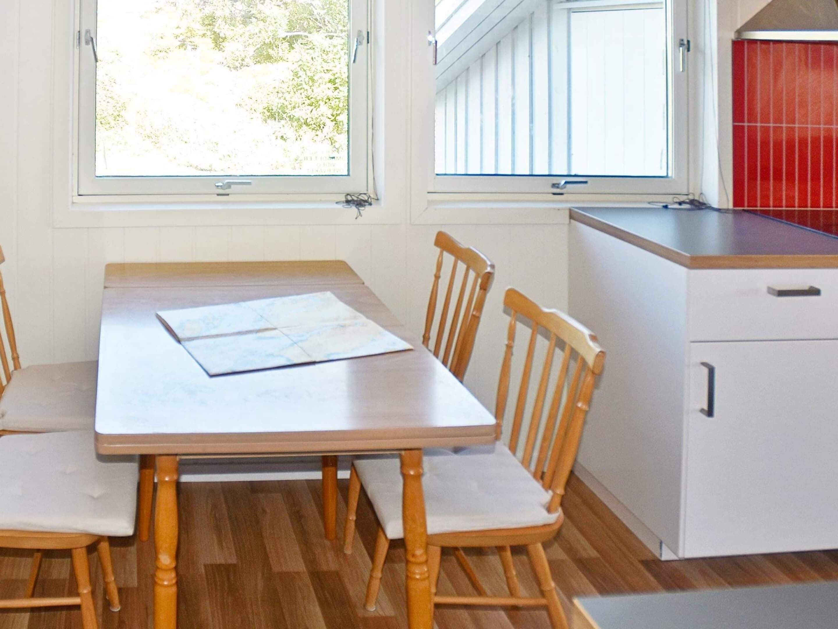 A dining area with a table and chairs, a window, and a kitchen area with cabinets.