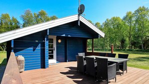 A blue cabin with a deck, outdoor furniture, and a satellite dish. - 4 Person Holiday Home in Bindslev (Bindslev)