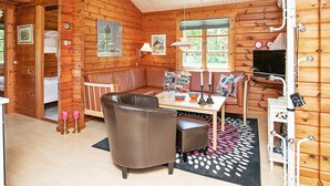 A cabin with a wooden interior, a sofa, a table with bowls, a lamp, and a television. - 4 Person Holiday Home in Bindslev (Bindslev)