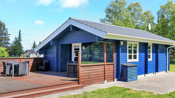 A blue building with a covered patio, a grill, and a small deck. - 4 Person Holiday Home in Bindslev (Bindslev)