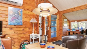 A wooden cabin interior with a dining table, chairs, a lamp, and a painting on the wall. - 4 Person Holiday Home in Bindslev (Bindslev)