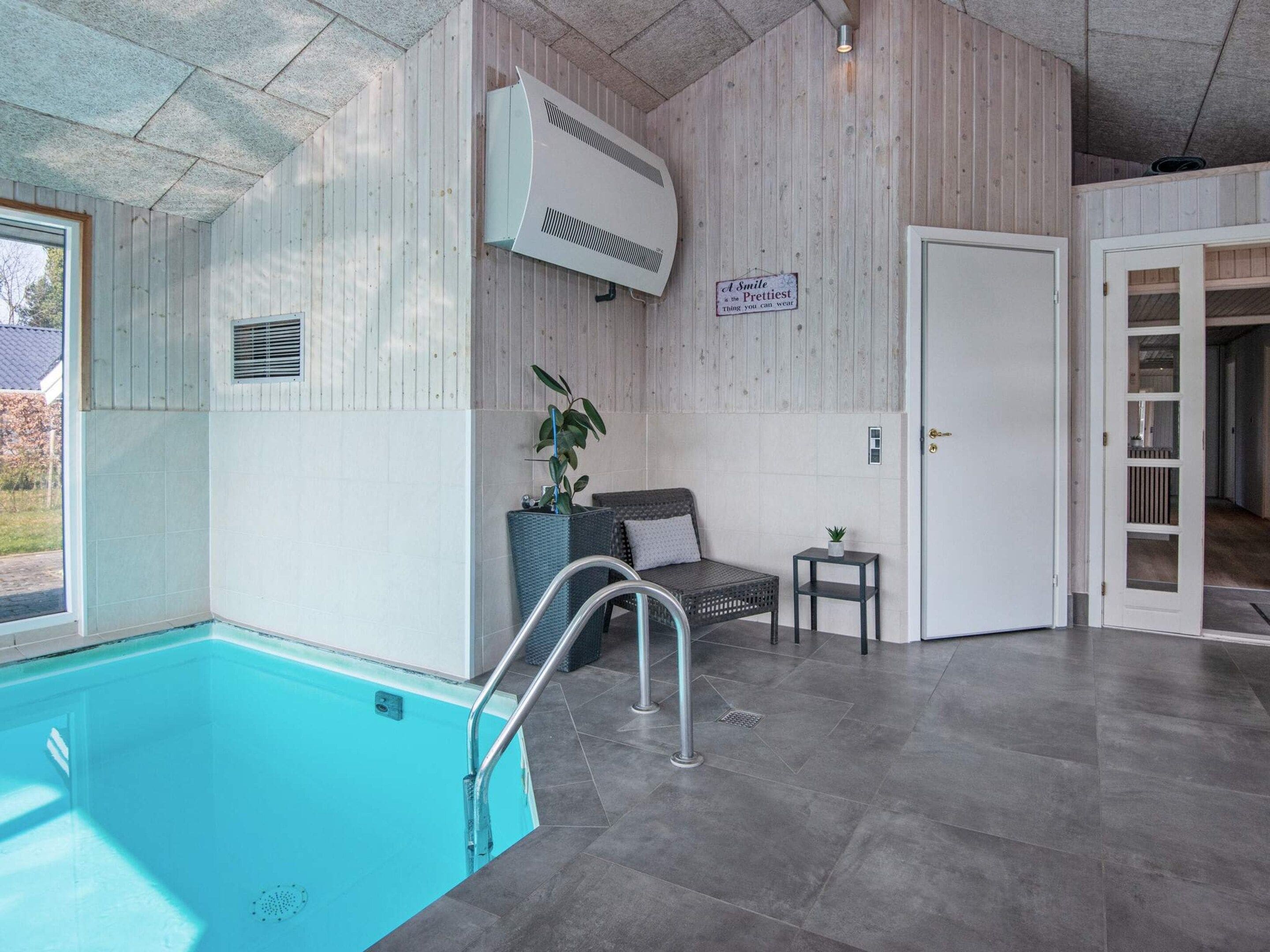 A pool area with a clear view of the pool, a seating area with a chair and a small table, and a door leading to another room.
