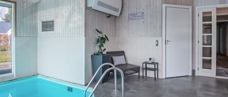 A pool area with a clear view of the pool, a seating area with a chair and a small table, and a door leading to another room.