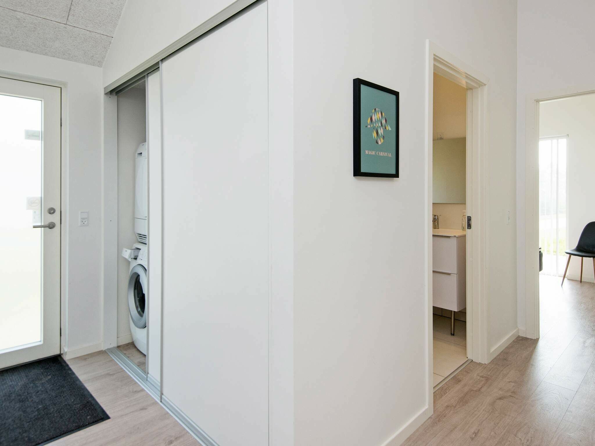 En moderne lejlighed med vaskefaciliteter, et indrammet kunstværk og udsigt til et køkken.