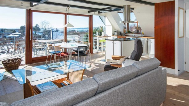 Um interior moderno com área de jantar, cozinha e espaço para sentar, com grandes janelas.
