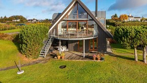 Uma casa moderna com fachada de vidro ampla, deck de madeira e chaminé.