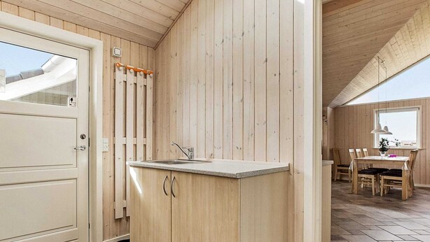 A compact kitchen with wooden cabinets, a sink, and a dining area with a table and chairs.