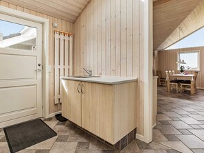A compact kitchen with wooden cabinets, a sink, and a dining area with a table and chairs. - Lakeview Retreat in Kvie So - By Traum Ferienwohnungen (Ansager)
