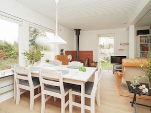 A dining area with a white table and chairs, a black heater, and a view of the outdoors. - Vibrant Holiday Home in Nykobing Sj near Sea (Nykobing Sjaelland)