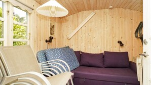 A wooden interior with a sofa, chairs, and a hanging light fixture. - Vibrant Holiday Home in Nykobing Sj near Sea (Nykobing Sjaelland)