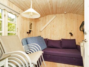 Un interior de madera con un sofá, sillas y una lámpara colgante.