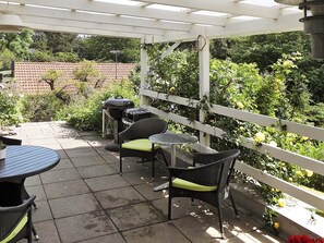 An outdoor patio with a grill, seating, and a view of a garden. - Vibrant Holiday Home in Nykobing Sj near Sea (Nykobing Sjaelland)