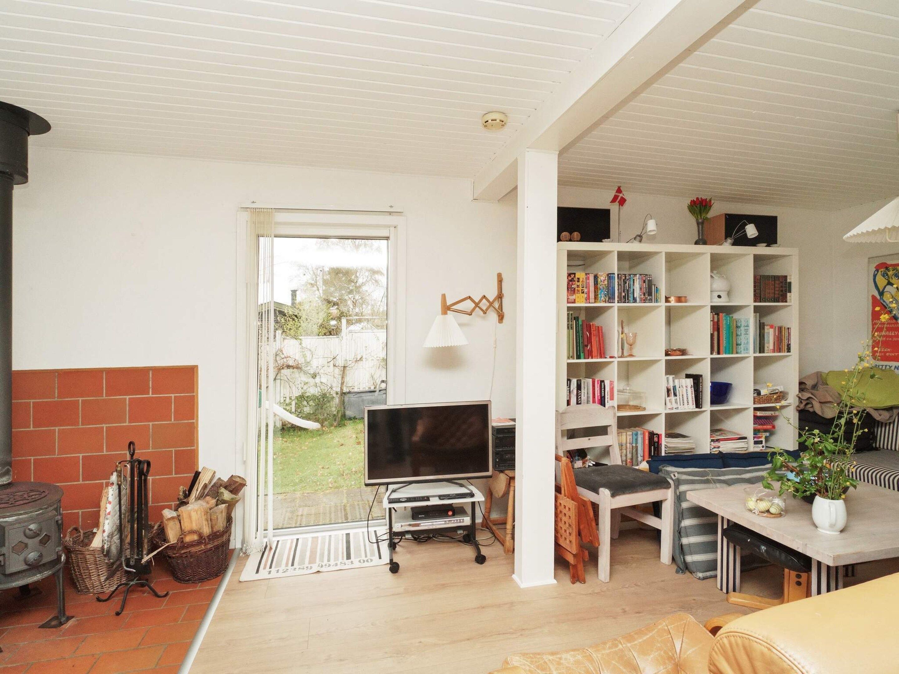 A living room with a fireplace, a television, a bookshelf, and a dining area.