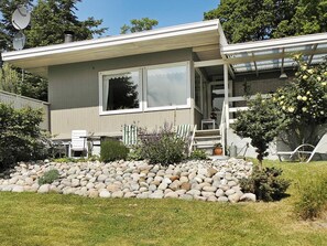 A single-story house with a front porch, a small garden with rocks and plants, and a satellite dish on the roof. - Vibrant Holiday Home in Nykobing Sj near Sea (Nykobing Sjaelland)