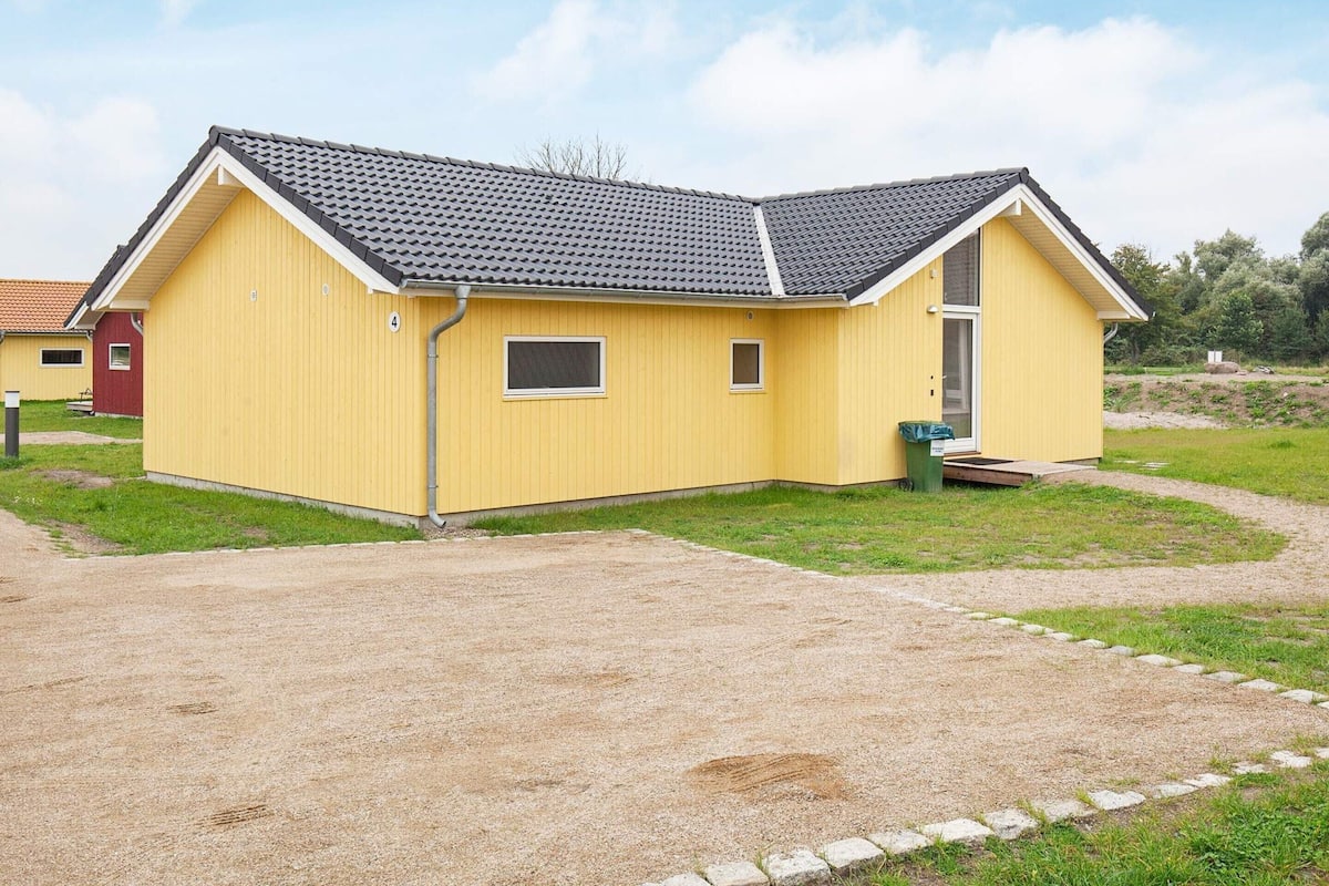 Un bâtiment jaune avec un toit gris, une petite fenêtre et une porte.