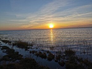 A sunset over a calm body of water with sparse vegetation in the foreground. - 7 Person Holiday Home in Bredebro (Bredebro)