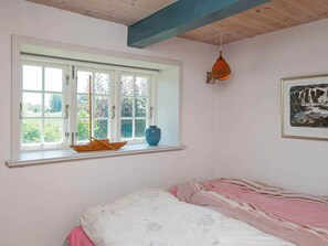 Quarto com uma cama, janela com vista, um vaso e um quadro.
