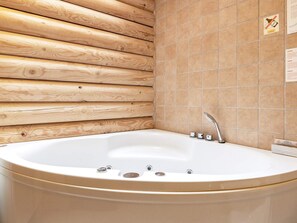 A bathroom with a wooden wall, a tiled wall, and a white bathtub with a faucet. - 12 Person Holiday Home in Saeby-by Traum (Sæby)