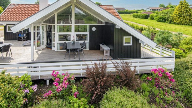 Une maison moderne dotée d’une grande terrasse, d’un coin repas et d’un patio couvert.