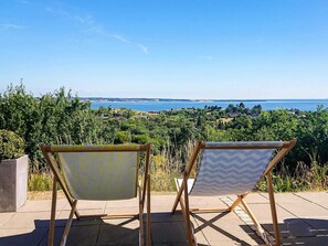 Two folding chairs with patterned fabric facing a scenic view of a coastal landscape.
