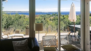 Une pièce avec vue sur la mer, un canapé, deux fauteuils et une lampe.