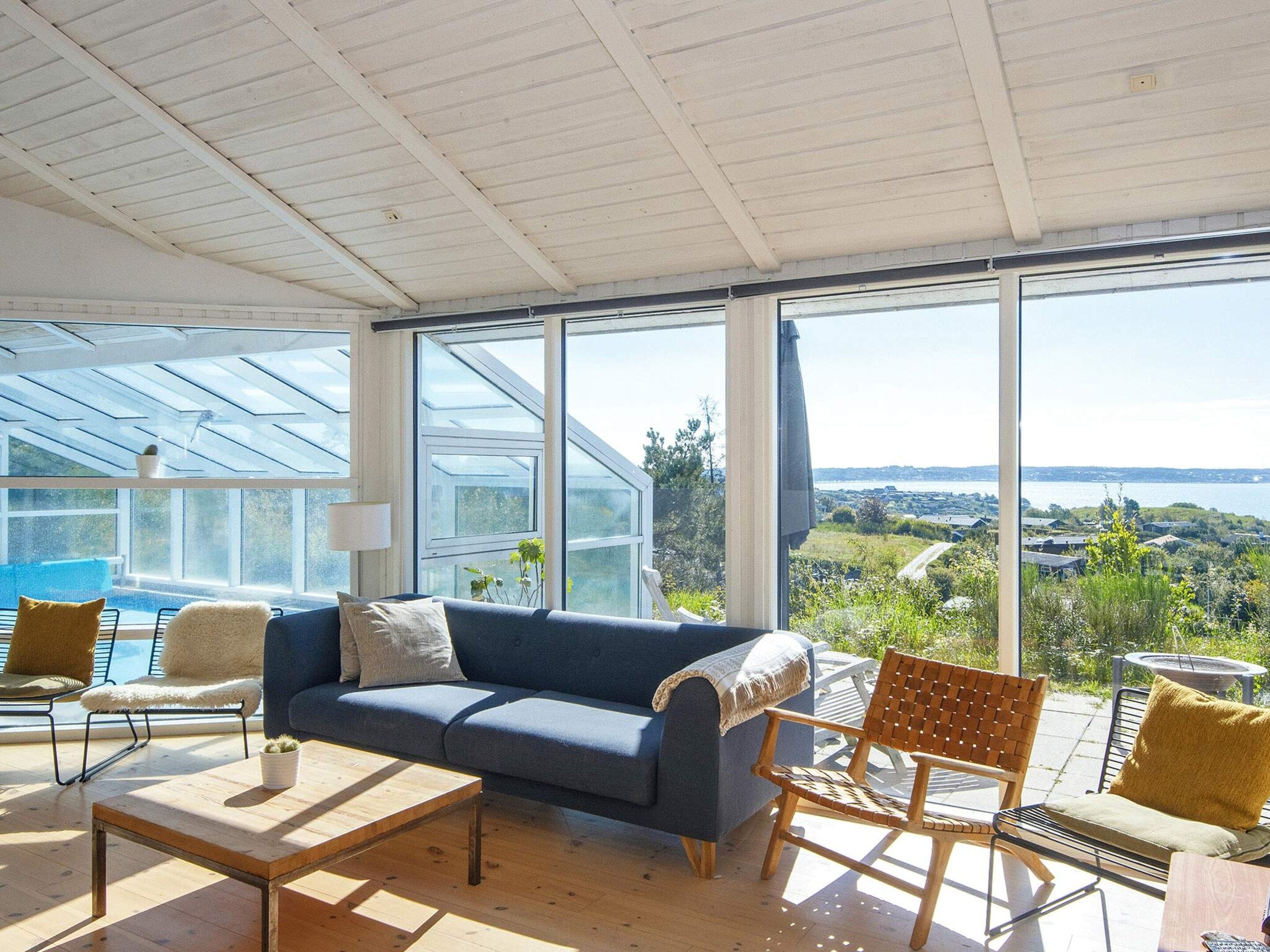 A modern living room with a blue sofa, wooden coffee table, and a view of a coastal landscape.