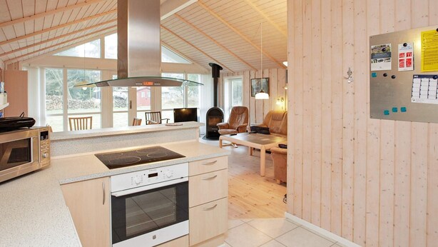 A modern kitchen with a large island, built-in oven, and a stainless steel range hood.