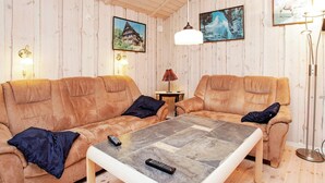 A cozy room with two sofas, a coffee table, and a lamp. There are paintings on the walls and a floor lamp.