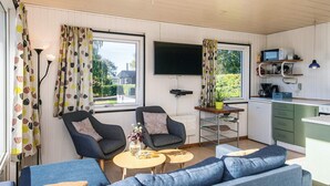 A compact living space with a sofa, chairs, a small table, a TV, and a kitchenette. - Scenic Holiday Home in Hejls near Sea (Hejls)