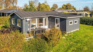 A modern mobile home with a patio area, large windows, and a well-maintained lawn. - Scenic Holiday Home in Hejls near Sea (Hejls)