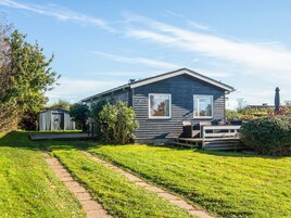 A single-story house with a covered patio area, a small shed, and a well-maintained lawn.