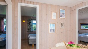 A room with wooden walls, a bed, a table with a basket, and framed pictures on the wall. - Scenic Holiday Home in Hejls near Sea (Hejls)