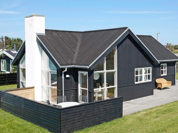 Una casa moderna con esterno scuro, ampie finestre e una zona relax esterna coperta.