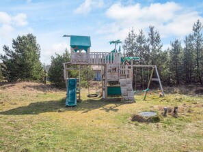 Una estructura de joc de fusta amb tobogan, cadira de balanç i elements per escalar.